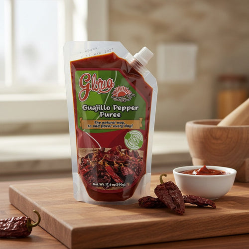 Gloria Guajillo Pepper Puree packaging on a wooden cutting board with dried guajillo peppers.